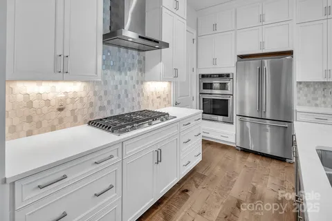 a kitchen with granite countertop a refrigerator stove and white cabinets