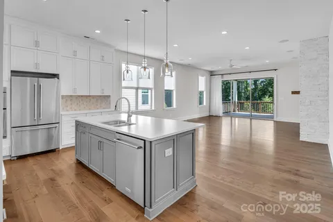 a kitchen with stainless steel appliances granite countertop a sink a window and wooden floor