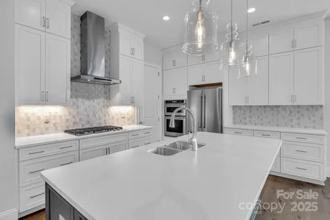 a kitchen with stainless steel appliances granite countertop a sink a stove a refrigerator and cabinets