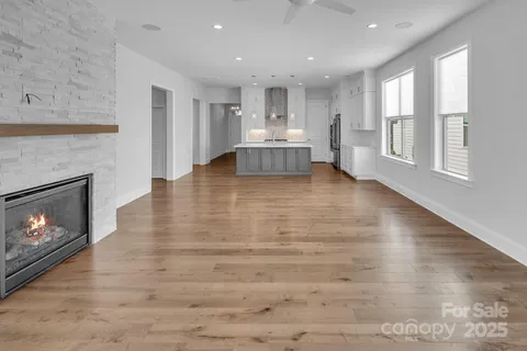 a view of an empty room with wooden floor and a fireplace