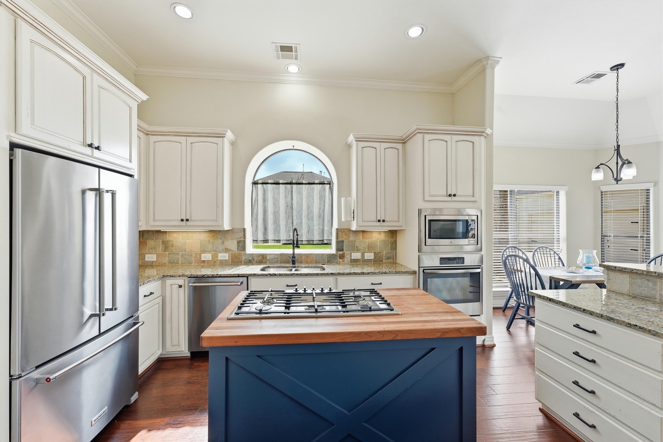 4810 Magnolia Bend Drive Rosharon, TX 77583 - Photo 12 of 40 Another view of this bright and inviting kitchen with stainless steel appliances, island, and elegant cabinetry. The arched window above the sink adds charm, while the open layout seamlessly connects to the dining area.