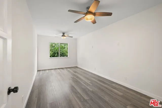 an empty room with wooden floor chandelier fan and windows