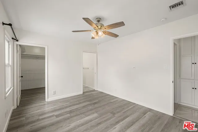 a view of an empty room with window and a ceiling fan