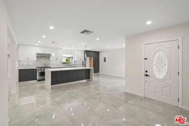 a large white kitchen with a lot of kitchen island and a sink