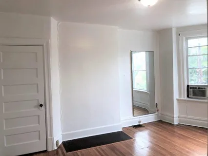 a view of an empty room with a window and wooden floor