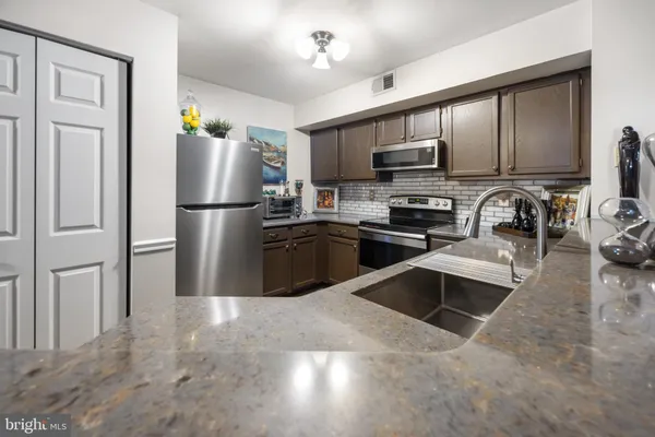 a kitchen with stainless steel appliances granite countertop a refrigerator a stove a sink and a microwave