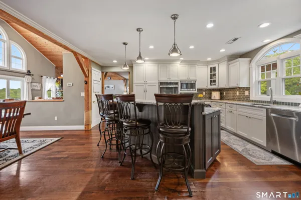 a kitchen with stainless steel appliances kitchen island granite countertop a table chairs sink and cabinets