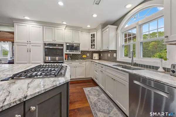 a kitchen with kitchen island granite countertop a sink a counter top space stainless steel appliances and windows