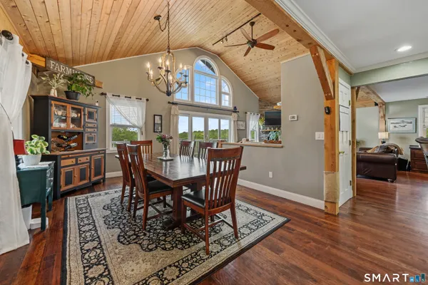 a dining room with wooden floor a chandelier a wooden table and chairs