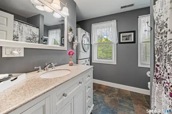 a bathroom with a granite countertop sink mirror vanity and a bathtub