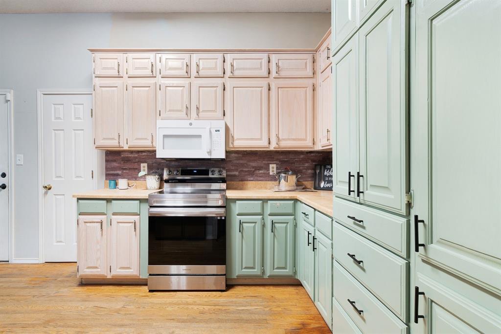 455 Timber Lakes Drive Powderly, TX 75473 - Photo 3 of 18 a kitchen with stainless steel appliances granite countertop a stove a sink and white cabinets