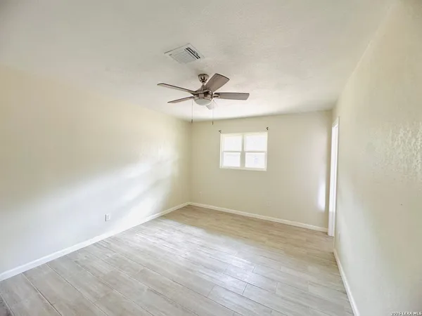 an empty room with wooden floor and ceiling fan
