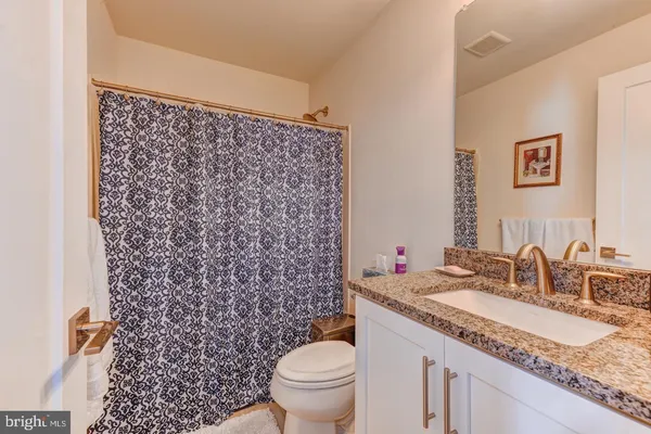 a bathroom with a granite countertop sink and a toilet