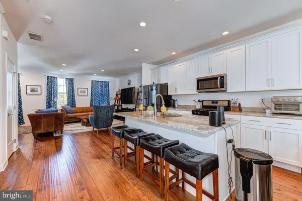 a kitchen with stainless steel appliances granite countertop a stove top oven a sink a dining table and chairs with wooden floor