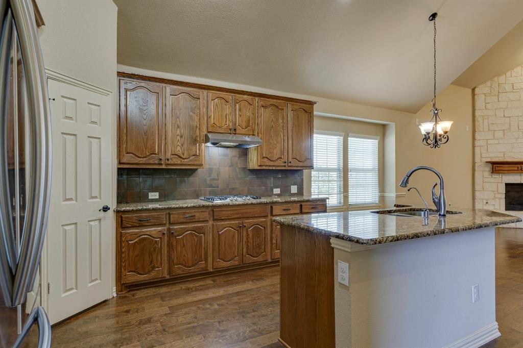 1522 Blue Jay Road Garland, TX 75043 - Photo 15 of 32 Kitchen featuring wood-finish cabinetry, granite countertops, and a stone tile backsplash