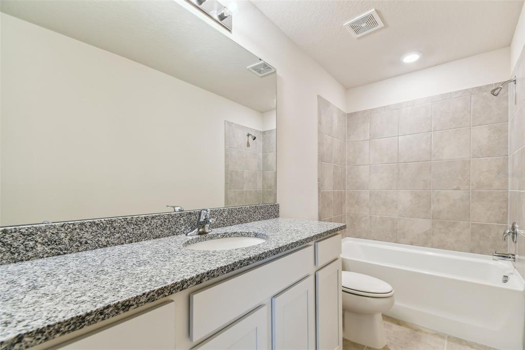 6793 Southwest 90th Loop Ocala, FL 34476 - Photo 20 of 23 a bathroom with a granite countertop sink a toilet and bathtub