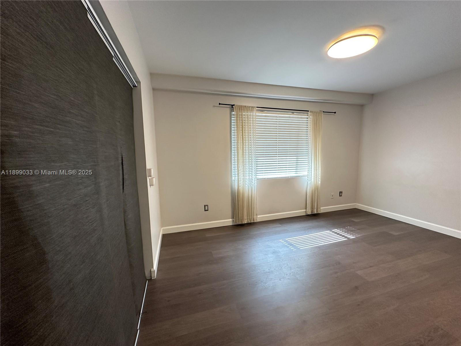 677 Northeast 24th Street, Unit 406 Miami, FL 33137 - Photo 9 of 15 an empty room with wooden floor and windows