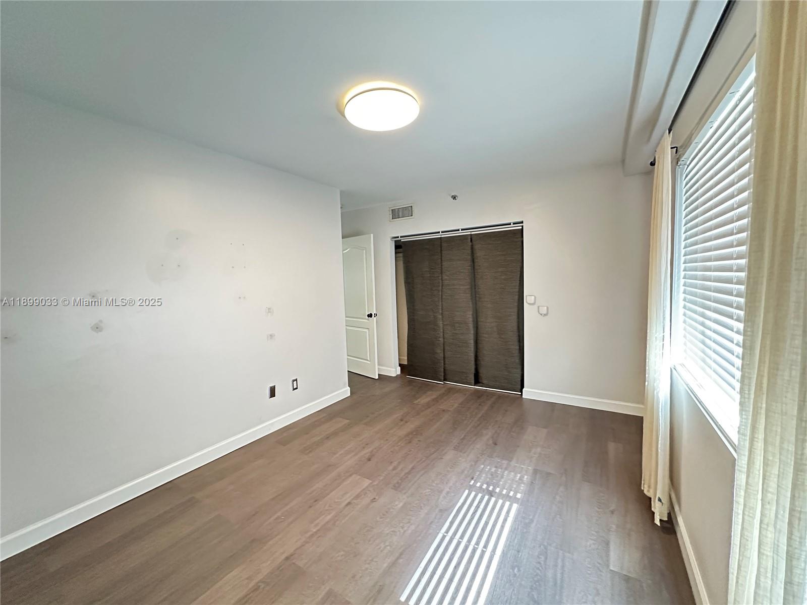677 Northeast 24th Street, Unit 406 Miami, FL 33137 - Photo 10 of 15 an empty room with wooden floor and windows
