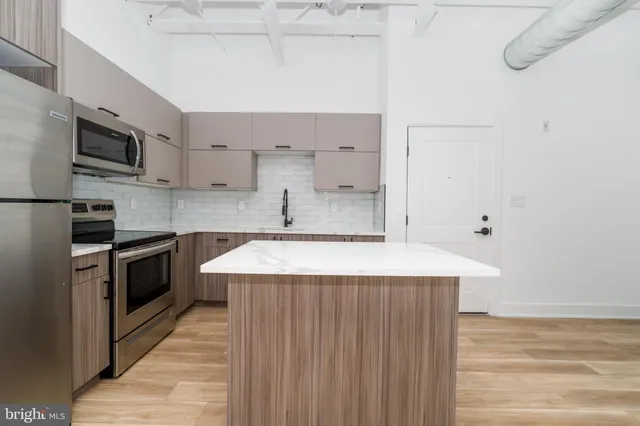 a kitchen with stainless steel appliances a sink cabinets and wooden floor