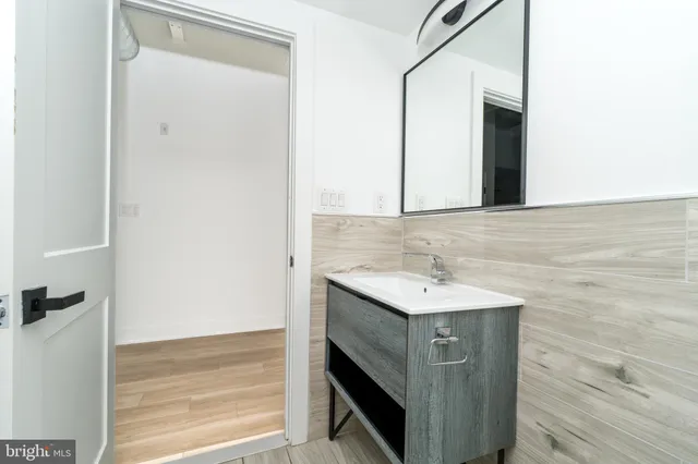 a view of a hallway with wooden floor and a bathroom