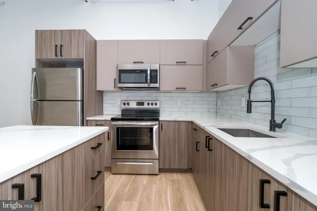 a kitchen with kitchen island a stove top oven and sink