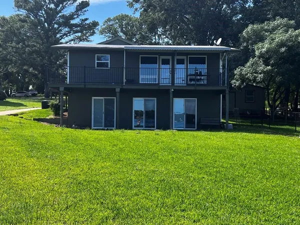 a view of a house with a yard and large tree