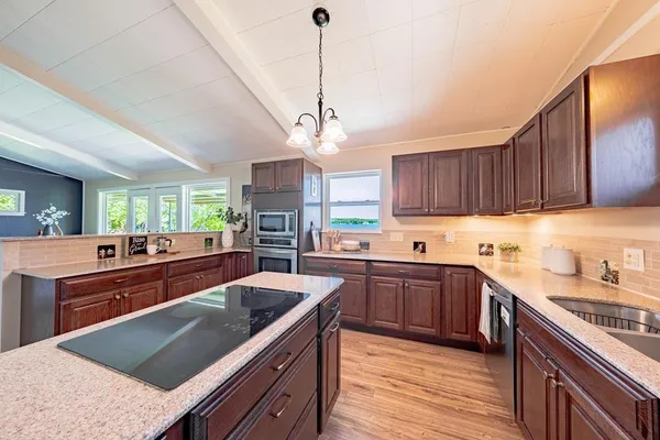 a kitchen with stainless steel appliances granite countertop wooden cabinets sink stove and granite counter top