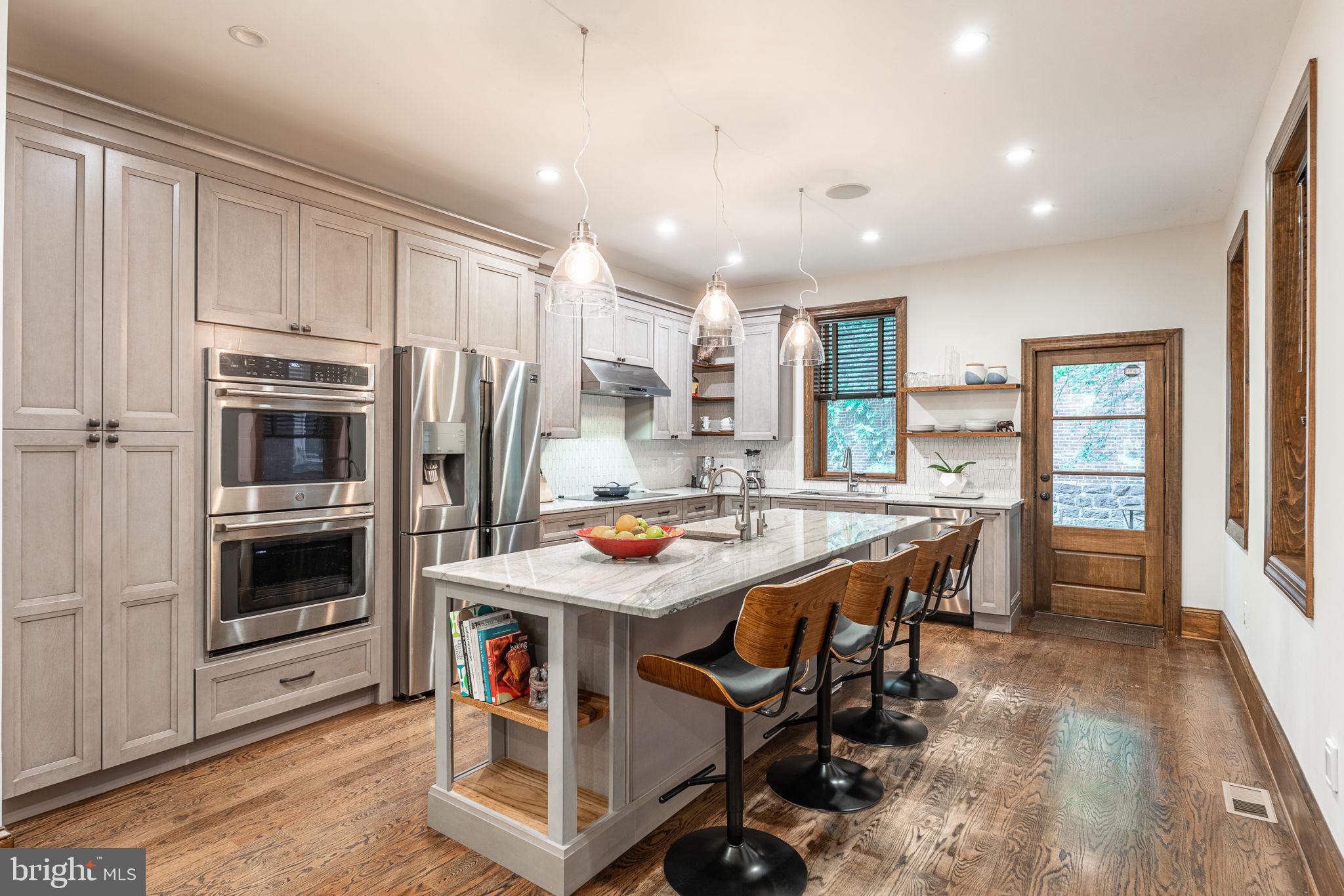 239 South 46th Street Philadelphia, PA 19139 - Photo 8 of 34 a kitchen with stainless steel appliances kitchen island granite countertop a stove a refrigerator a sink a dining table and chairs with wooden floor