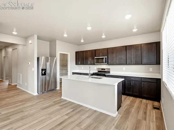 a kitchen with stainless steel appliances granite countertop a refrigerator a sink dishwasher a stove and white countertops with wooden floor