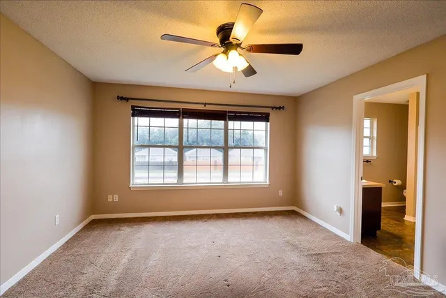 an empty room with windows and fan