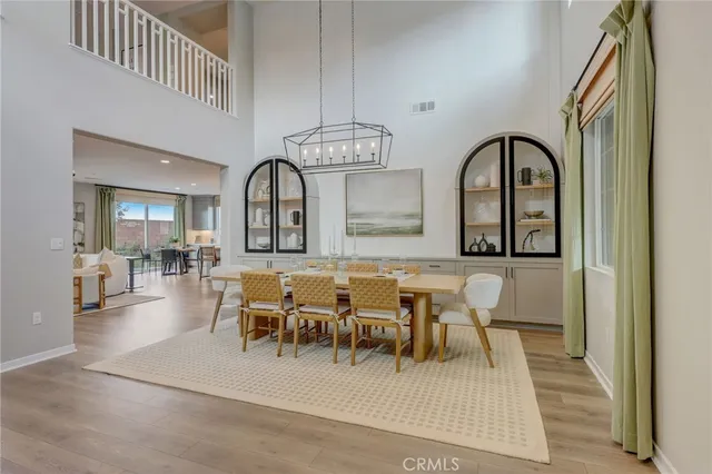 a dining room with wooden floor a chandelier a wooden table and chairs