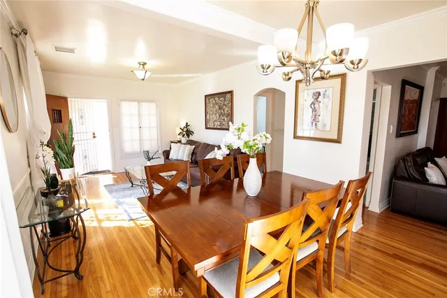 a dining room with wooden floor a chandelier a wooden table and chairs