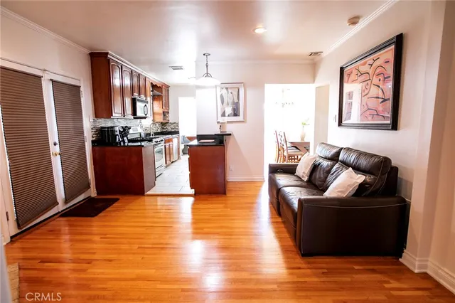a living room with stainless steel appliances furniture refrigerator and wooden floor