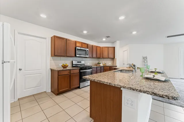 a kitchen with kitchen island granite countertop a stove sink and cabinets