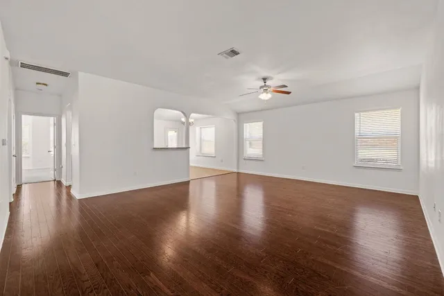 a view of an empty room with a window and wooden floor