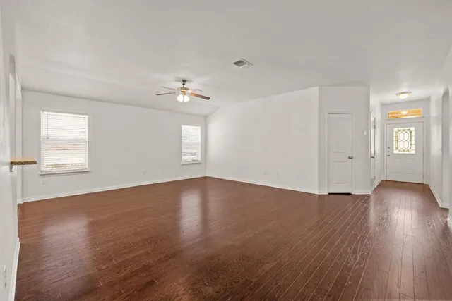 an empty room with wooden floor and windows