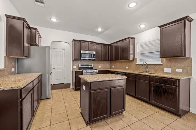 a kitchen with stainless steel appliances granite countertop wooden cabinets sink stove and refrigerator