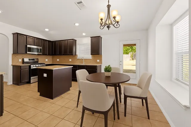 a kitchen with stainless steel appliances granite countertop a stove a sink a microwave a dining table and chairs with wooden floor