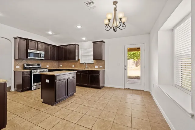 a large kitchen with stainless steel appliances granite countertop a stove a sink a microwave a counter space and cabinets