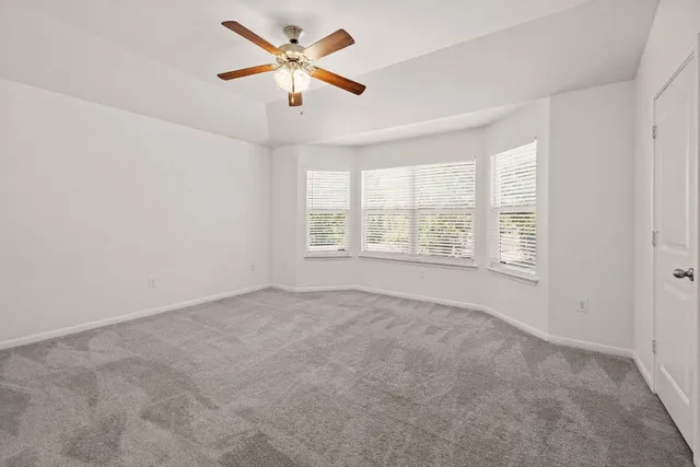 an empty room with windows and ceiling fan