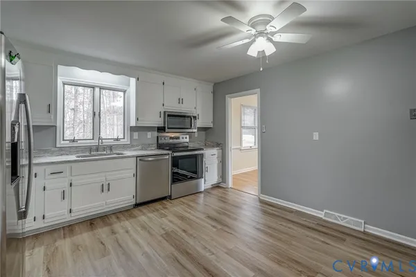 a kitchen with cabinets wooden floor and a ceiling fan