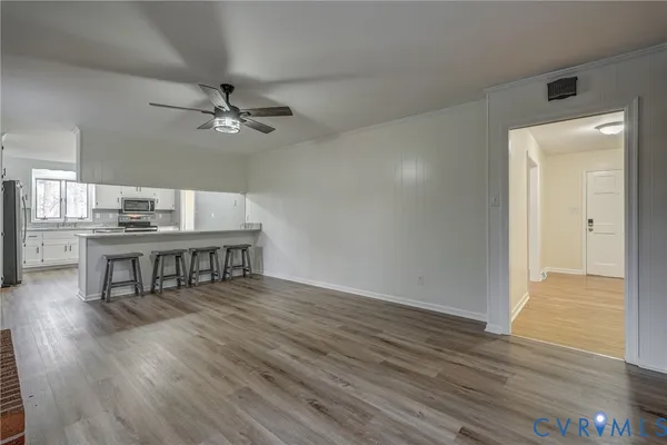 a view of an empty room with wooden floor and a window