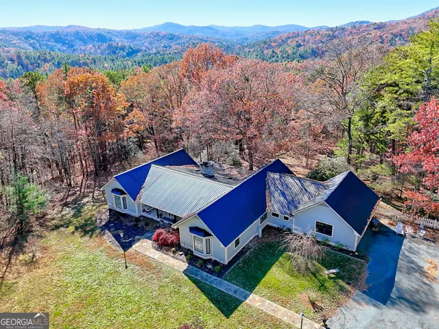 a view of a house with a big yard and large trees