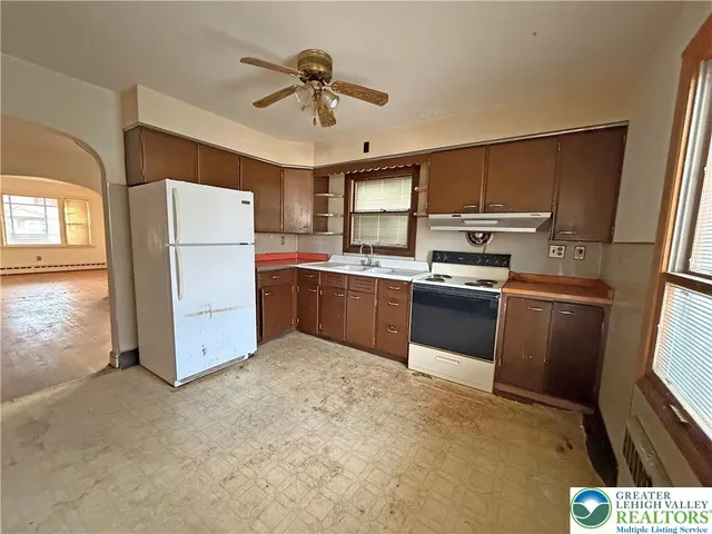 a kitchen with stainless steel appliances a refrigerator a sink a stove a microwave a dining table and chairs