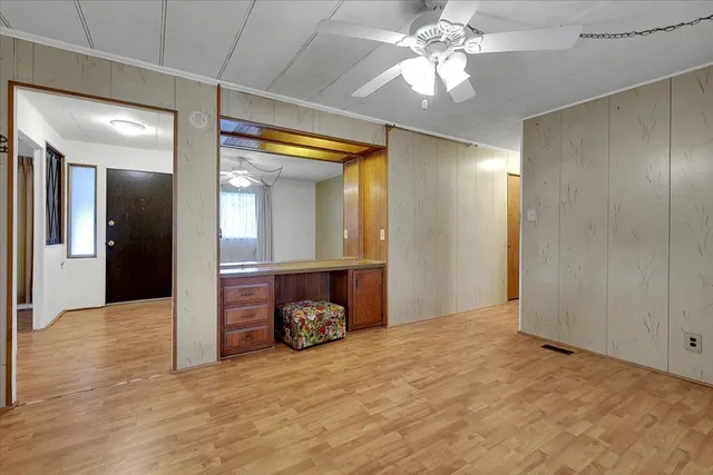 a view of a livingroom with a chandelier fan and wooden floor