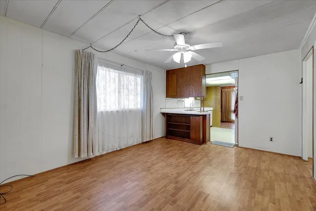 an empty room with a kitchen and a ceiling fan window