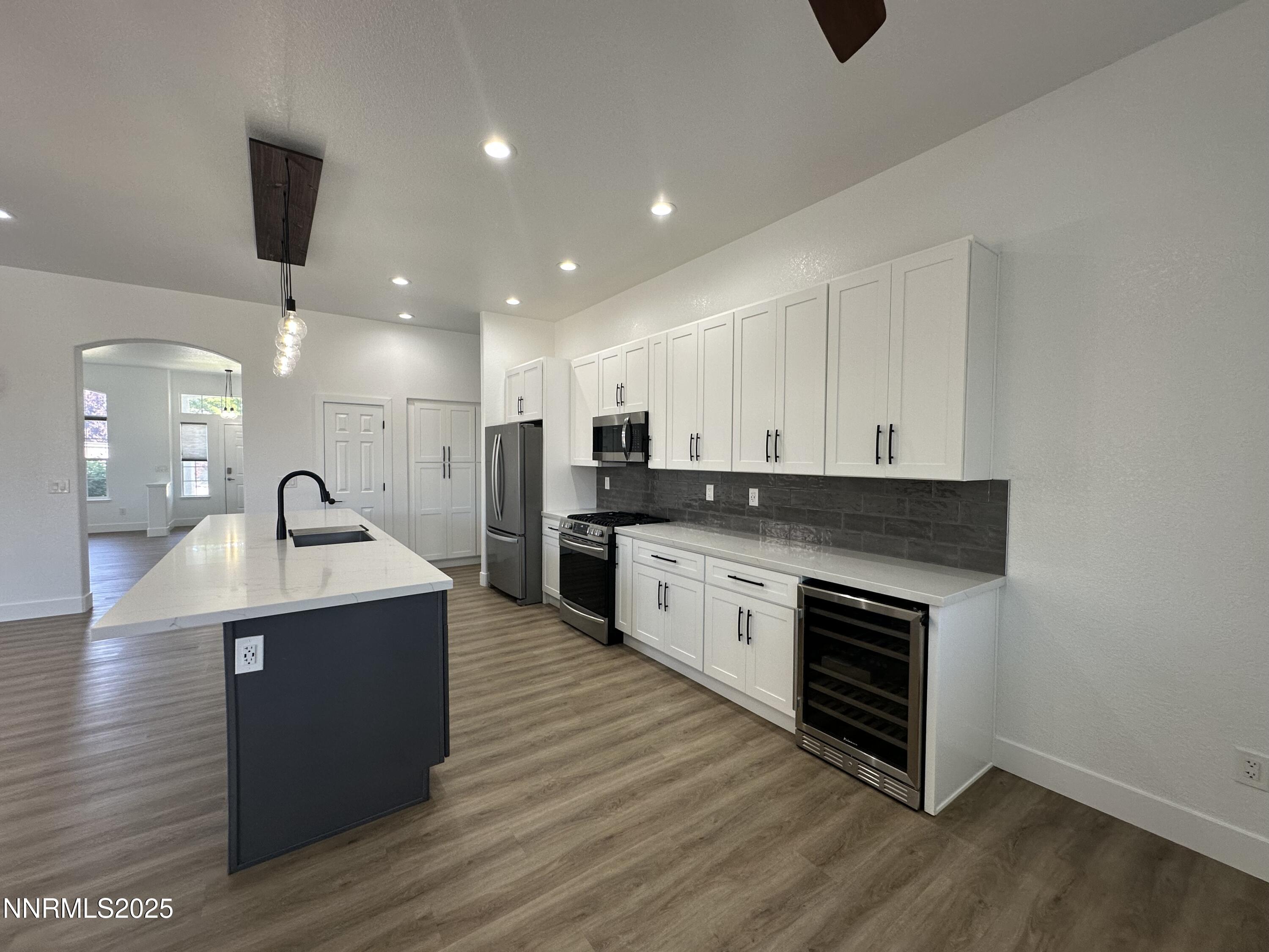 9533 Steep Climb Court Reno, NV 89521 - Photo 13 of 34 a large kitchen with stainless steel appliances kitchen island a large counter top and a stove with wooden floor