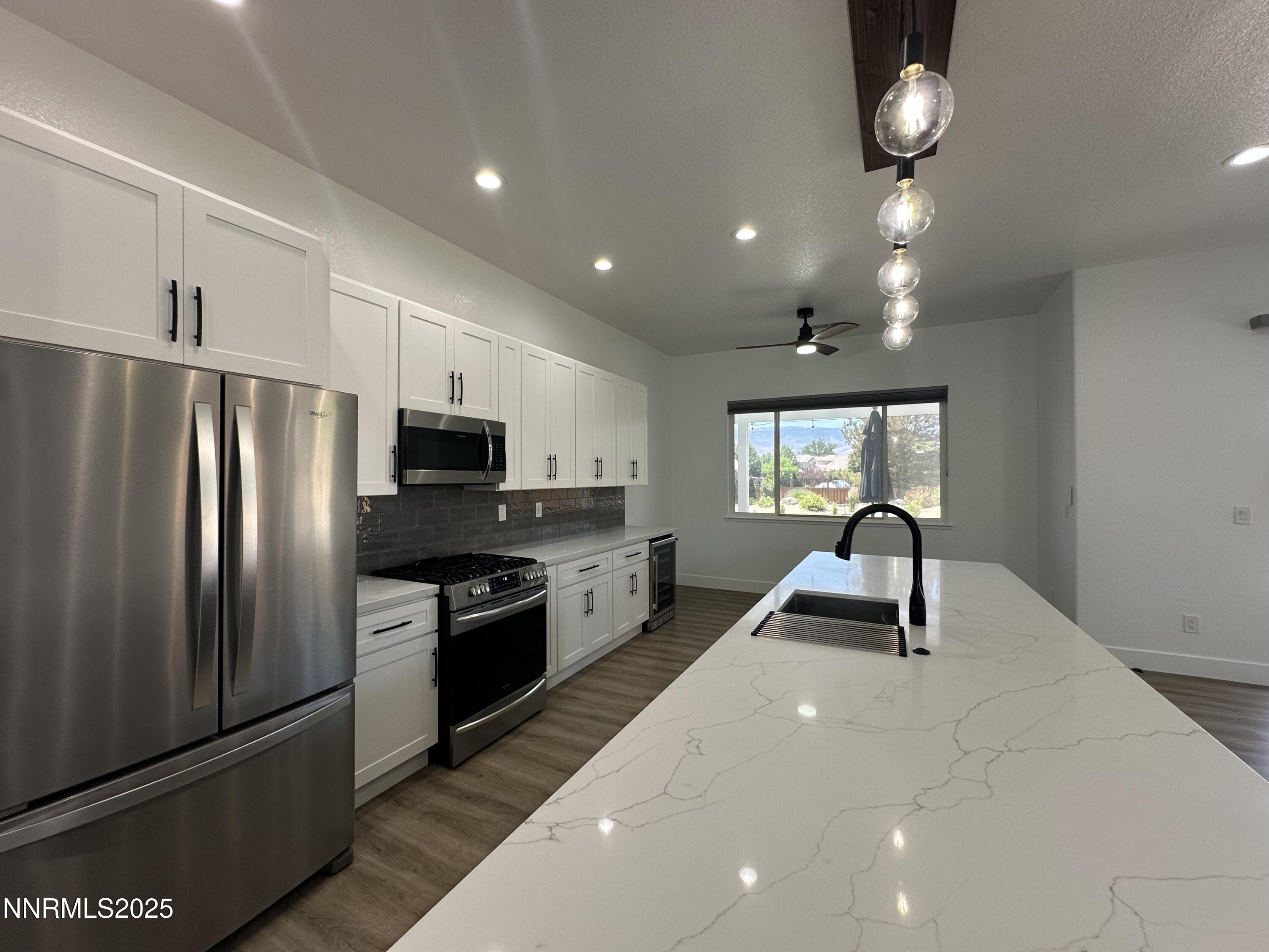 9533 Steep Climb Court Reno, NV 89521 - Photo 14 of 34 a kitchen with stainless steel appliances granite countertop a refrigerator a sink dishwasher a oven with white cabinets and wooden floor