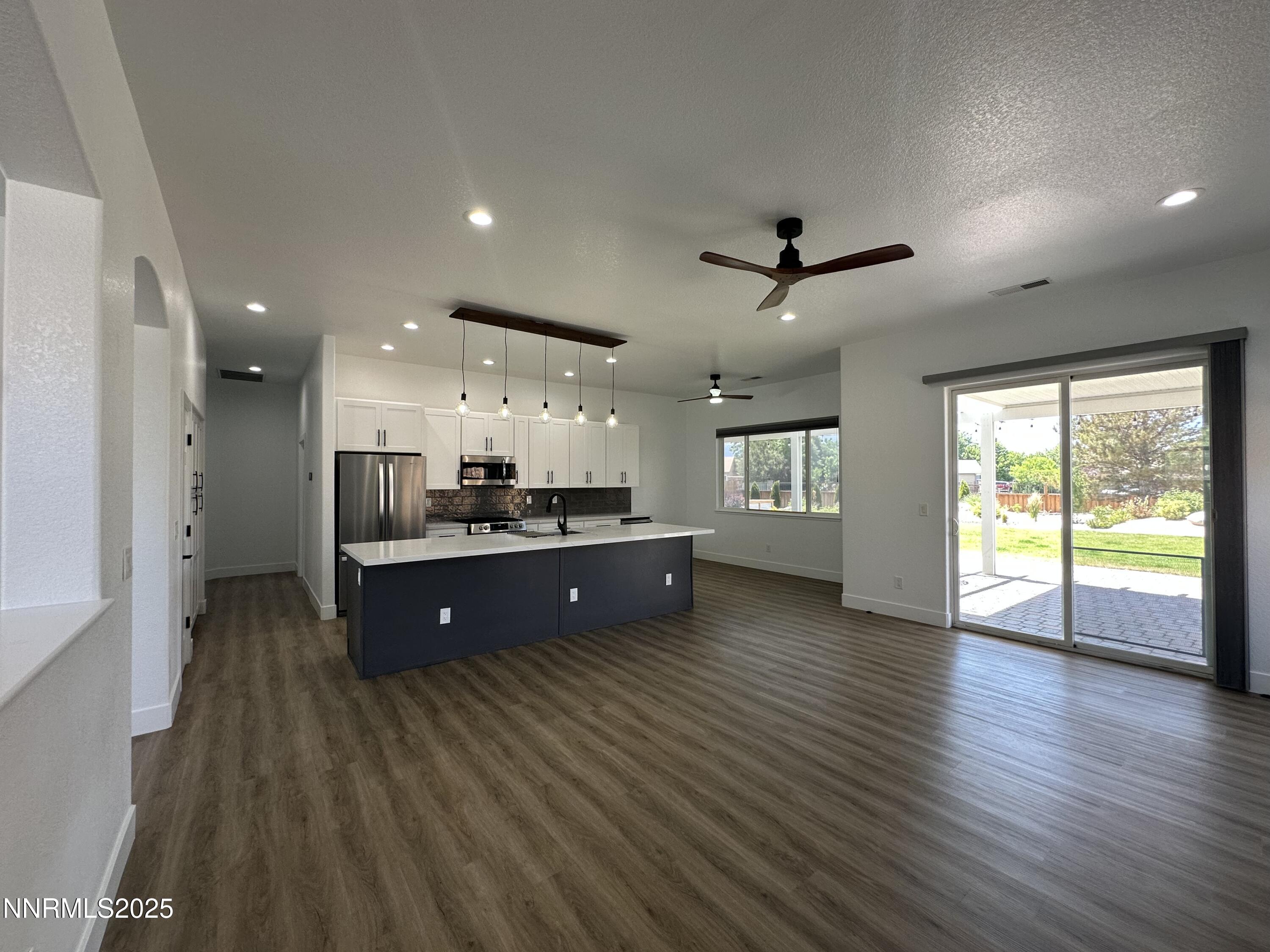 9533 Steep Climb Court Reno, NV 89521 - Photo 10 of 34 an empty room with wooden floor and a kitchen