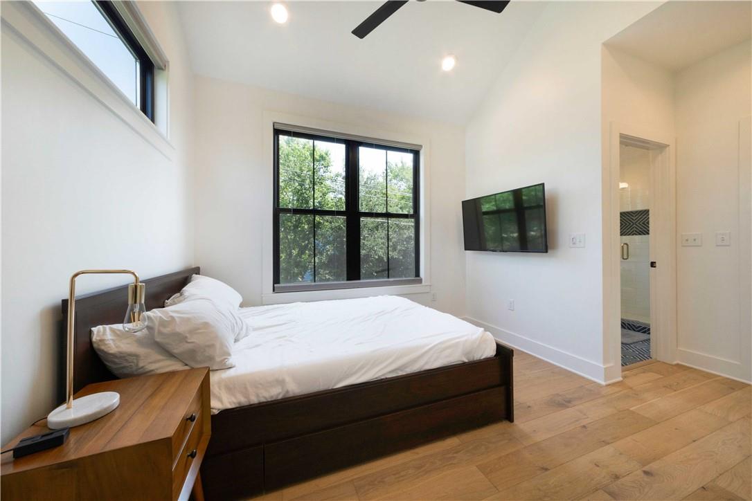 2002 East 9th Street, Unit 2 Austin, TX 78702 - Photo 15 of 32 Natural light floods this inviting bedroom, featuring warm wood flooring and a view of verdant foliage.